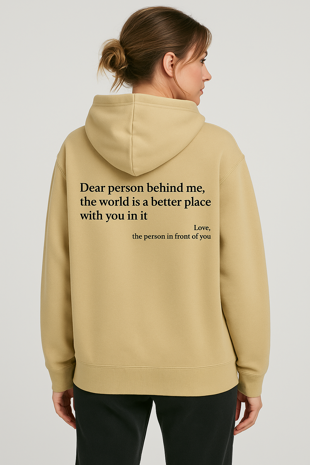 Person wearing a beige hoodie with a motivational quote on the back against a plain background