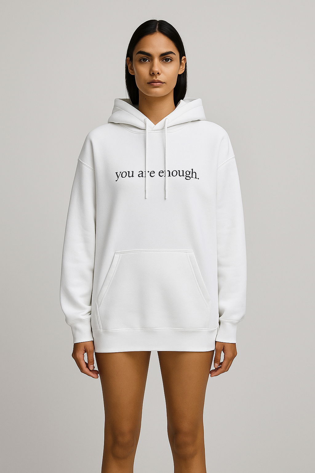 White hoodie with 'you are enough' text worn by a model on a gray background