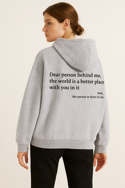 Person wearing a gray hoodie with a motivational quote on the back, standing against a plain background.