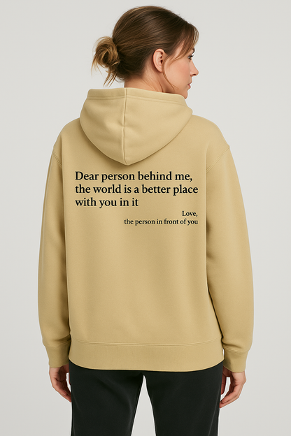 Person wearing a beige hoodie with a motivational quote on the back against a plain background