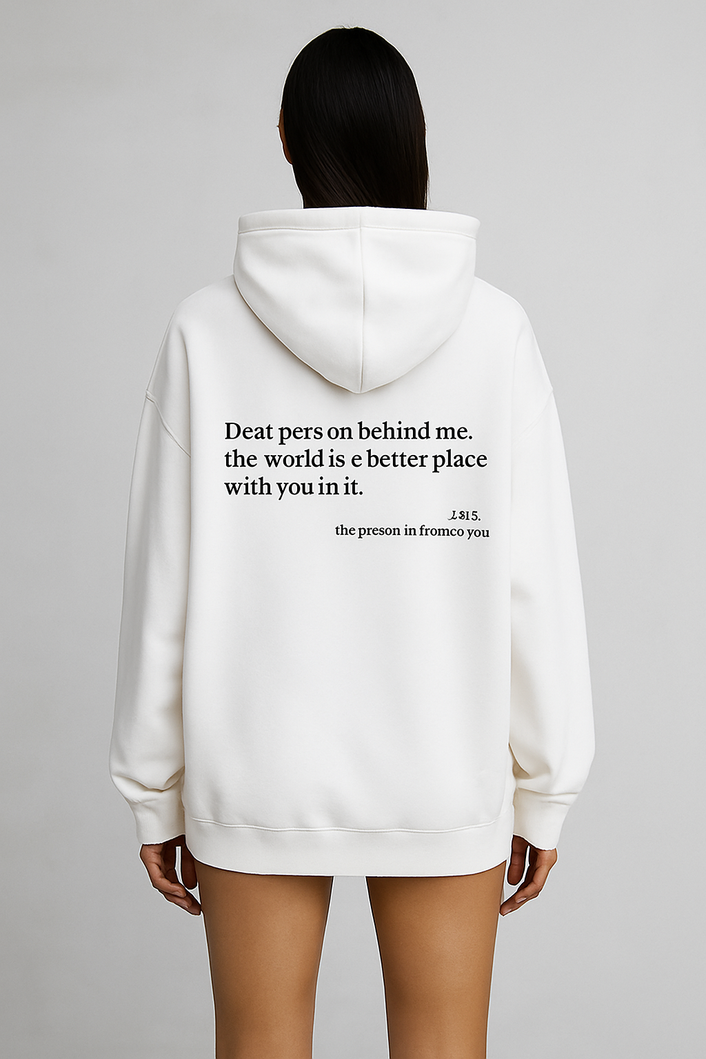 White hoodie with a motivational quote on the back, worn by a person against a gray background