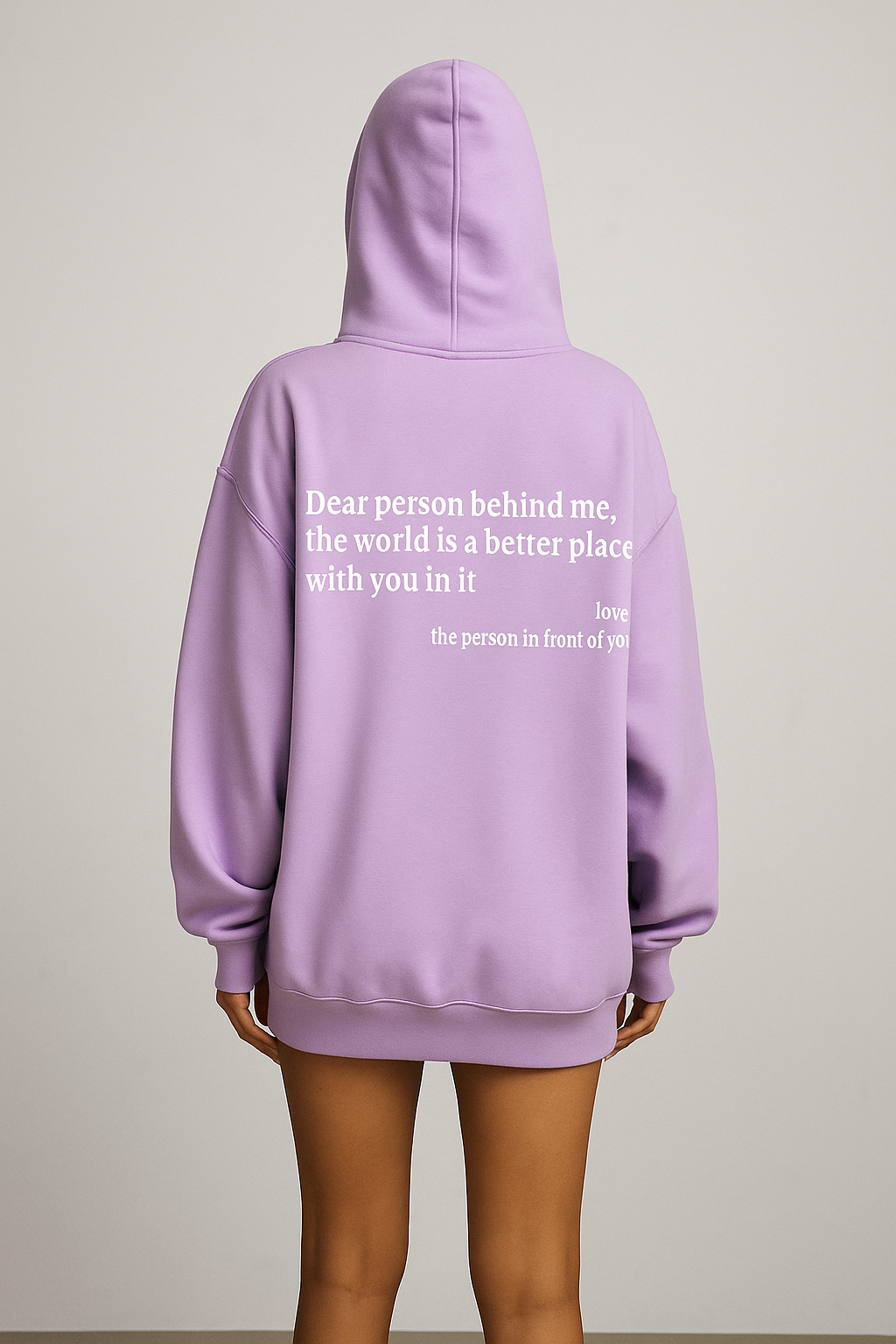 Person wearing a lavender hoodie with a message on the back against a plain background