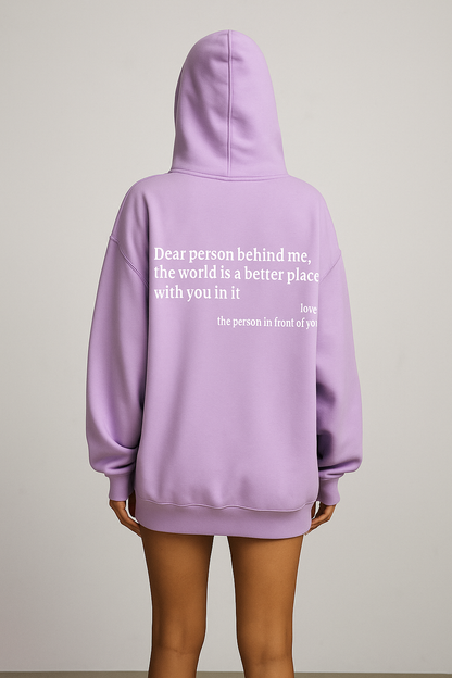 Person wearing a lavender hoodie with a message on the back against a plain background