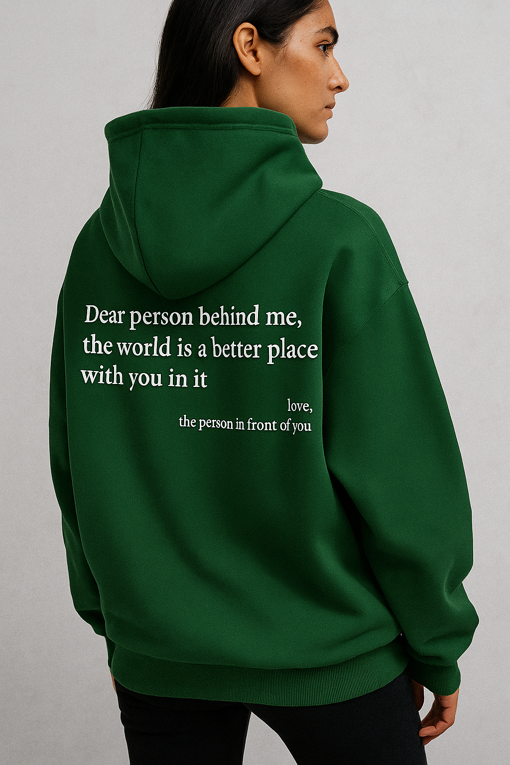 Person wearing a green hoodie with a message on the back against a gray background